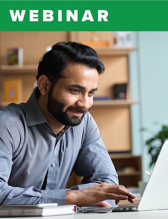 A bearded man smiles while moving the mouse on his laptop. 