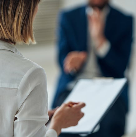 A woman holding a clipboard and looking at a man